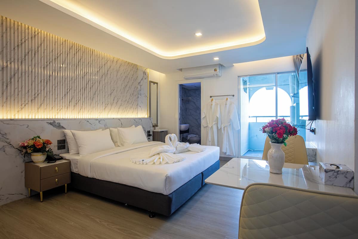 Habitación de hotel moderna con una cama grande, mesitas de noche, un escritorio y vistas al exterior.