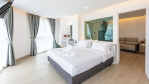 Una habitación de hotel moderna con una cama grande, un sofá, un espejo y vistas de la ciudad.