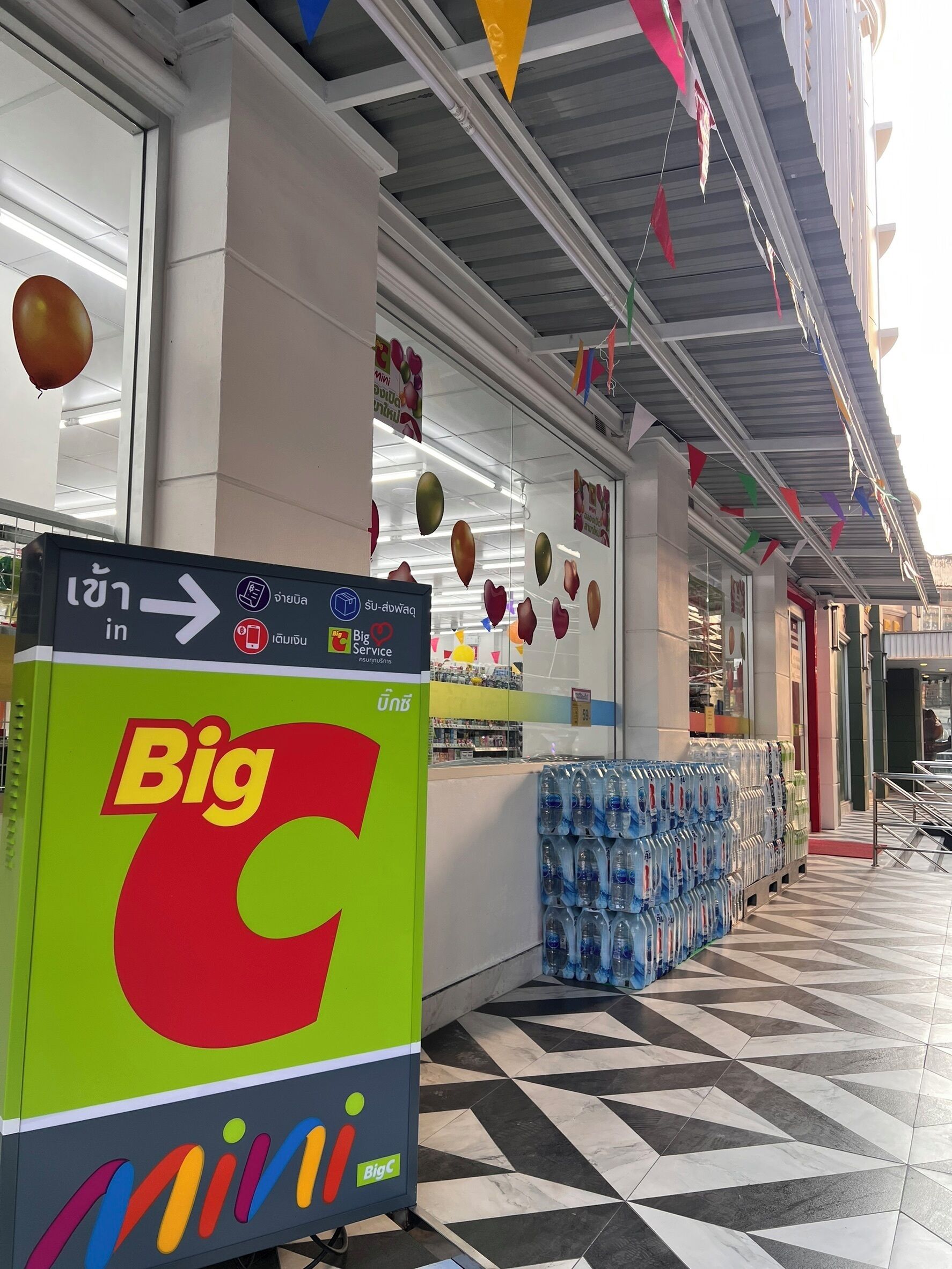 A Big C store with a clear sign, water bottles stacked outside, and a tiled floor.