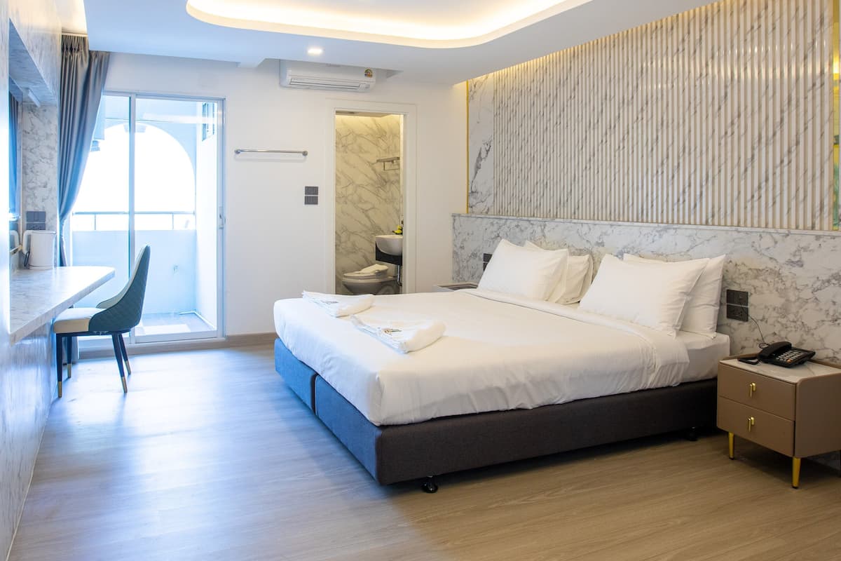 Una habitación de hotel moderna con una cama grande, un escritorio y un baño.