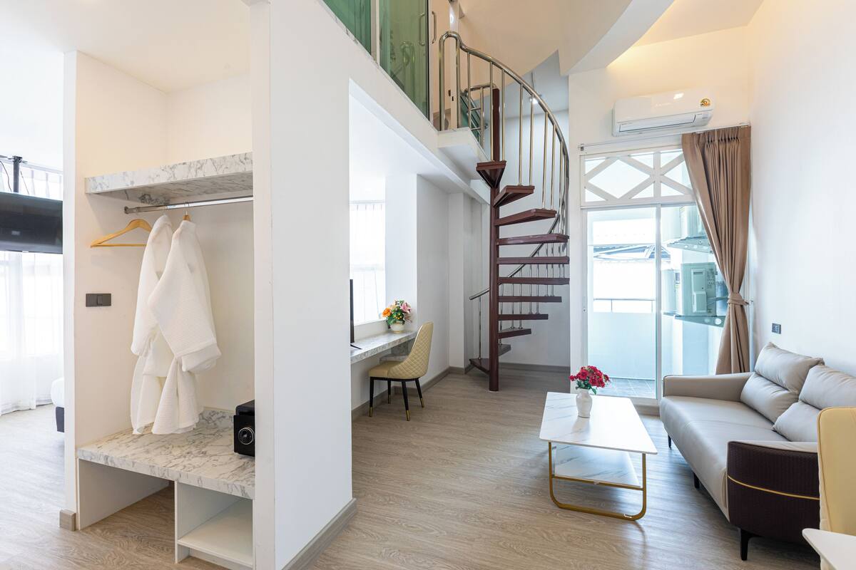 Una sala de estar moderna con un banco de mármol, un sofá, una mesa de centro y una escalera.