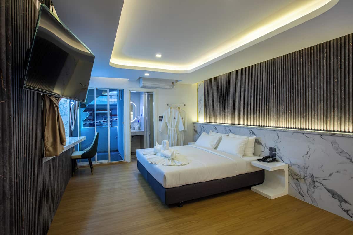 Una habitación de hotel moderna con una cama grande, un escritorio y un televisor.