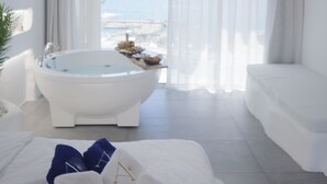 Un baño moderno con una bañera independiente, un amplio ventanal con vista al mar y un diseño minimalista.