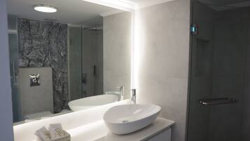 A modern bathroom with a large mirror, two sinks, and a walk-in shower.