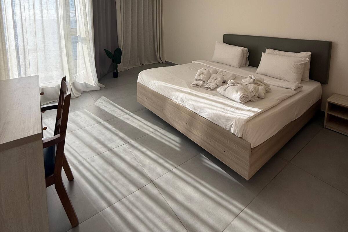 A hotel room with a large bed, a desk, and a chair.