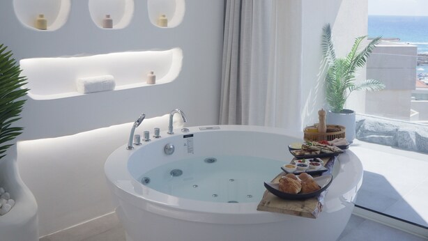 Un baño moderno con una bañera independiente, estantes empotrados y vistas al mar.