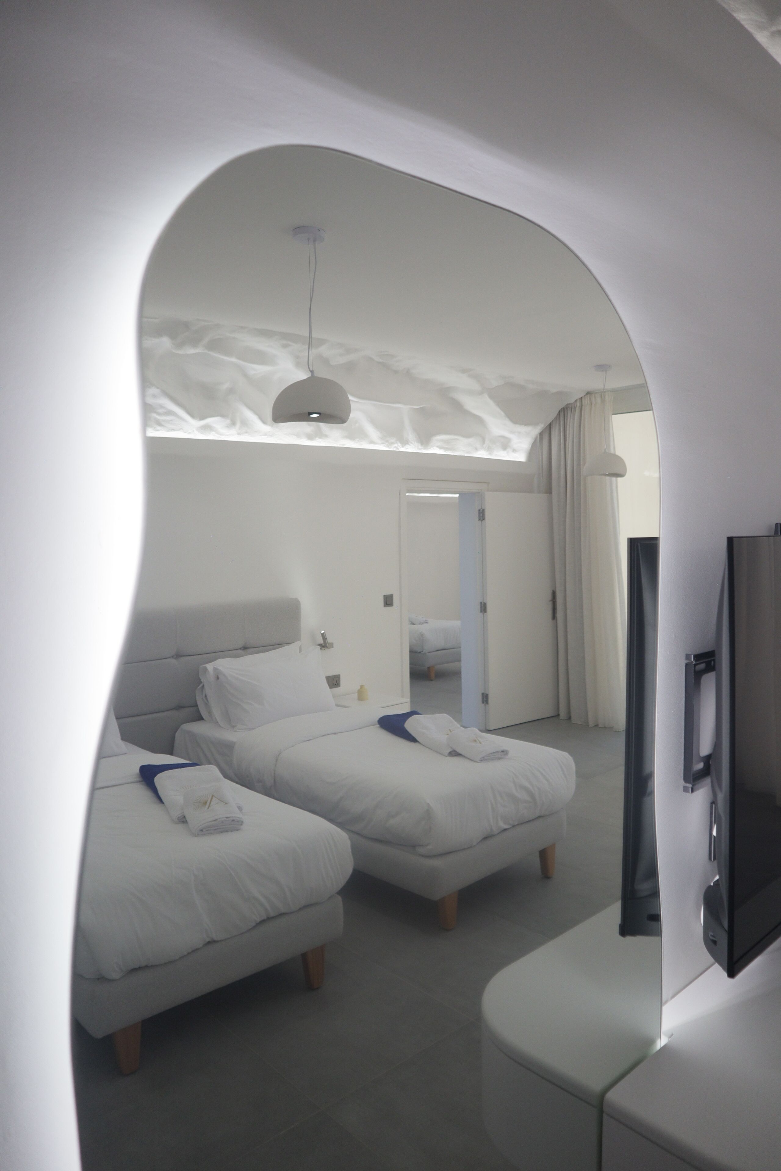 Een moderne hotelkamer met twee bedden, een flatscreen televisie en een groot raam.