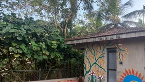 A rooftop terrace with a tiled floor, a door, and a wall with a mural of trees and flowers. - Casa ruya-Tierra (Benaulim)
