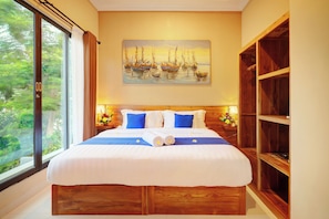 A hotel room with a large bed, a painting of boats on the wall, and a view of greenery through the window. - Villa Alessandra Seminyak (Bali)