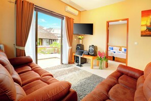 A living room with leather sofas, a flat-screen TV, a sound system, and a view of a residential area. - Villa Alessandra Seminyak (Bali)