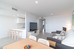 Una sala moderna con un sofá, televisión y comedor.