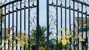 Una entrada protegida con intrincados trabajos de metal negro y detalles dorados, que da acceso a un edificio con un letrero que dice "LONGBEACH AAMU".