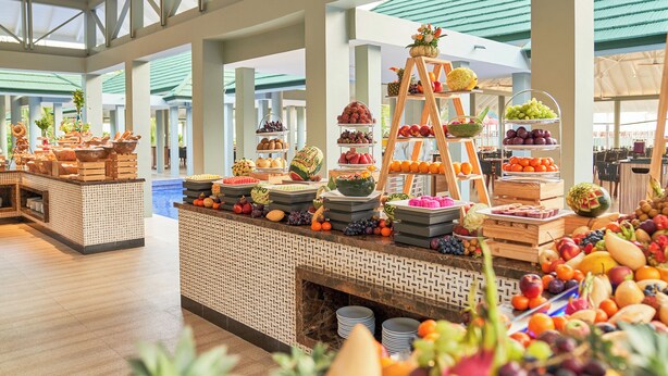 Montaje de bufé con frutas y verduras de diferentes tipos, expuestas en pedestales escalonados y cestas.
