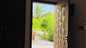Puerta abierta que da a un jardín con un sendero y palmeras.