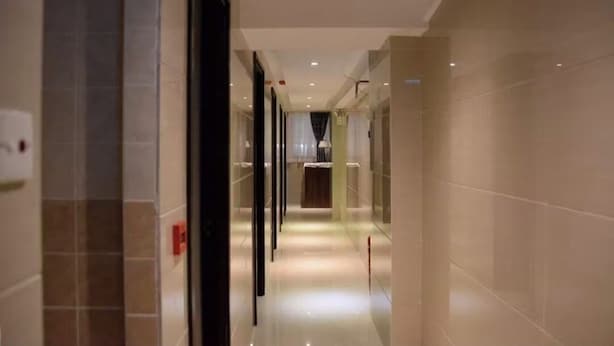 Un pasillo moderno de hotel con piso de baldosas limpias y una lámpara central.
