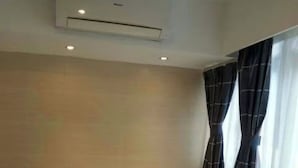 Una habitación de hotel pequeña y sencilla con dos camas, una mesita de noche, una lámpara y una ventana con cortinas.