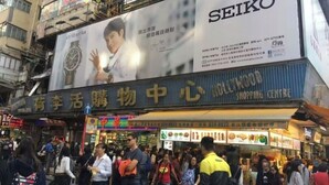 Una calle concurrida con un gran anuncio luminoso que promociona relojes Seiko.