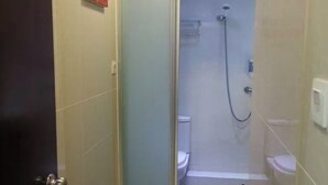 Cabina de ducha con paredes de vidrio, inodoro y ducha.
