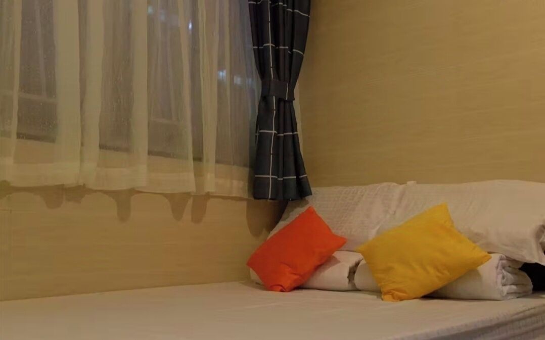 Une chambre avec un lit, une fenêtre avec des rideaux légers et une tringle à rideaux.
