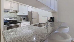 Una cocina moderna con encimeras de granito, electrodomésticos de acero inoxidable y muebles de cocina blancos.