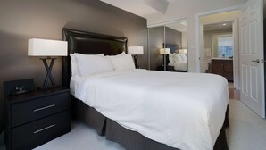 Una cama bien hecha con sábanas blancas, un cabecero oscuro y dos lámparas de noche.