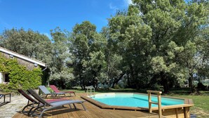 A wooden deck with a swimming pool, surrounded by trees and a house. - Le Mas d'Henriette  (Leyritz-Moncassin)