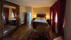 A bedroom with a bed, a chair, a table, and a mirror. - Le Mas d'Henriette  (Leyritz-Moncassin)