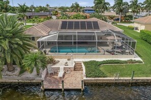 Enjoy a refreshing swim in the backyard pool surrounded by lush greenery and palm trees.