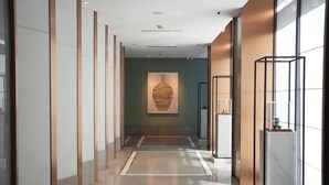 A modern hallway with a central art piece, a glass display case, and a marble floor. - Renhe Hotel (Hangzhou)