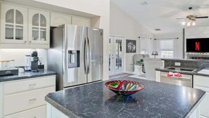 Una cocina moderna con electrodomésticos de acero inoxidable, encimera de mármol y un cuenco de vidrio colorido.
