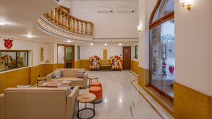 A hotel lobby with a curved staircase, seating area with sofas and ottomans, and a glass wall with a view. - Zone Connect by The Park Jaisalmer (Jaisalmer)