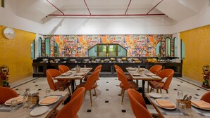 A restaurant with a long counter, orange chairs, and a colorful mural on the wall. - Zone Connect by The Park Jaisalmer (Jaisalmer)
