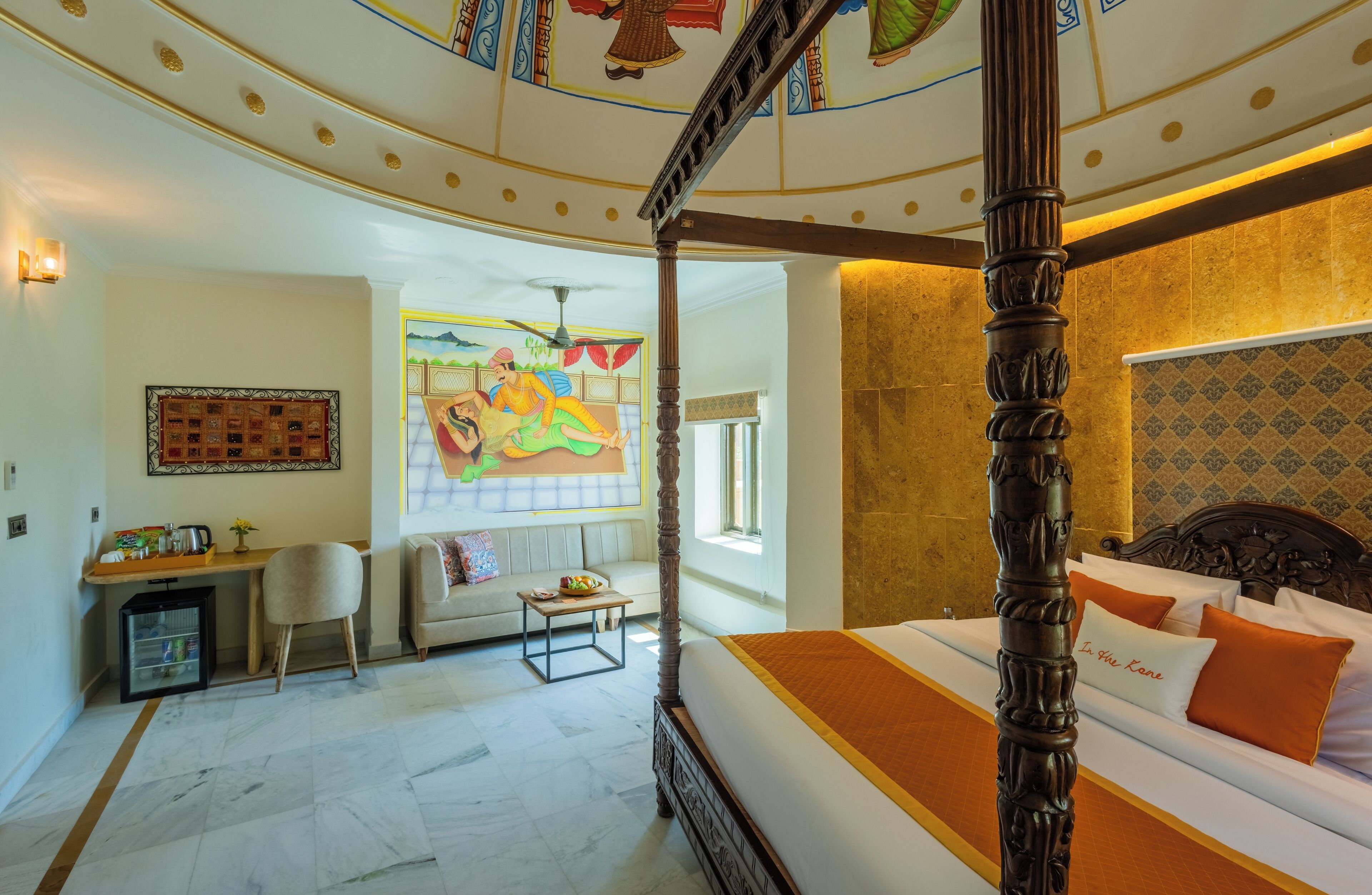 Una camera da letto con un letto a baldacchino, una scrivania con una sedia, un tavolino e un divano.