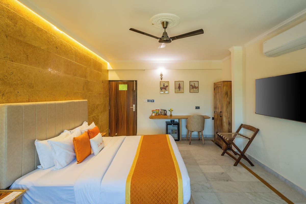 A hotel room with a bed, a desk, a chair, a television, and a ceiling fan.