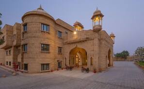 Un edificio histórico con una entrada imponente, varias ventanas y una torre destacada con luces.
