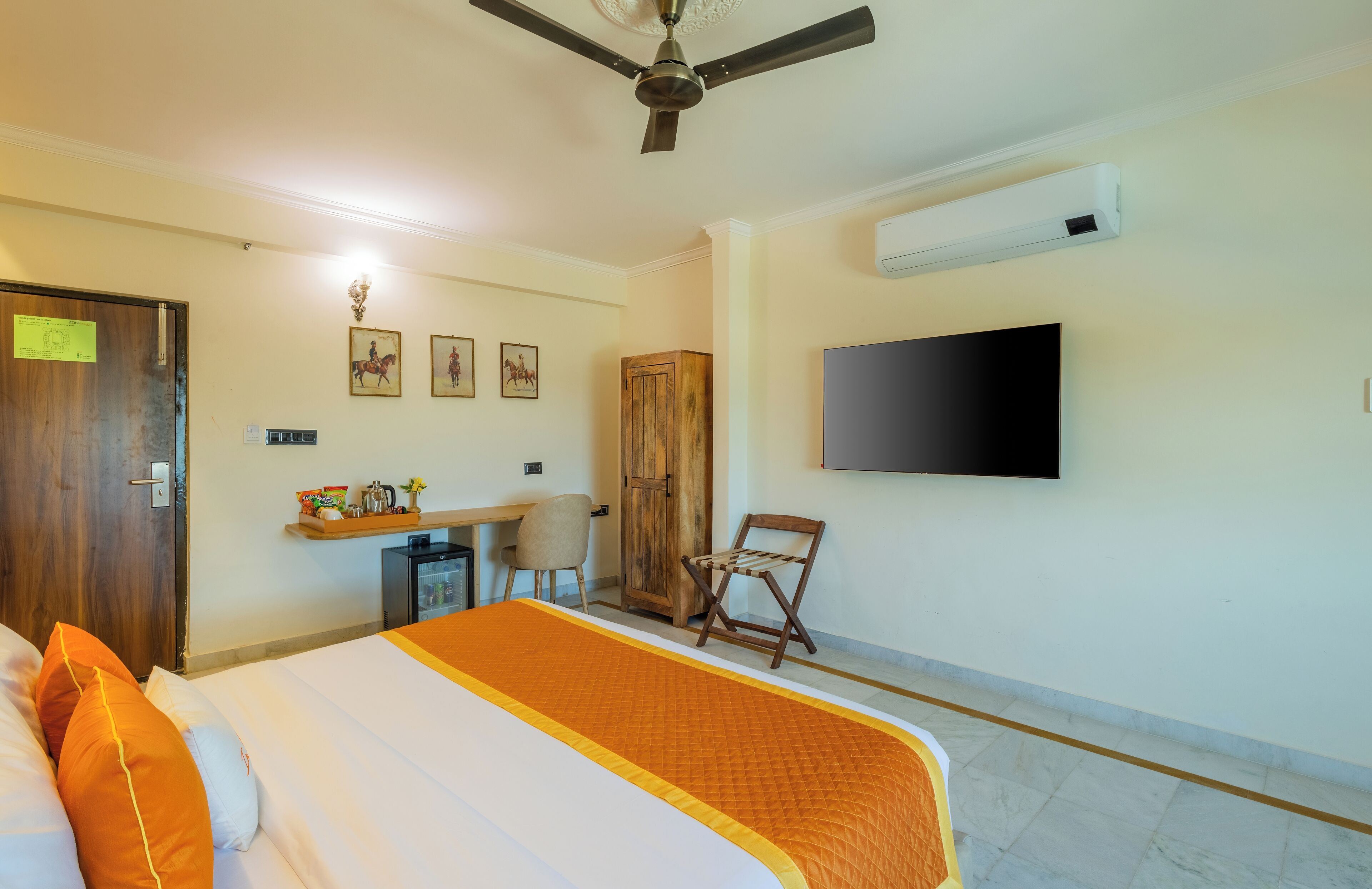 Una habitación de hotel con cama, escritorio, silla, televisor y armario.