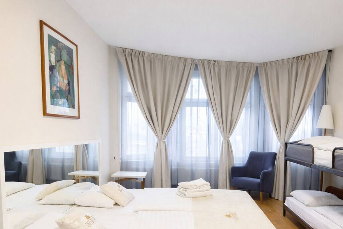 A hotel room with a large bed, a desk, a chair, and a bunk bed.
