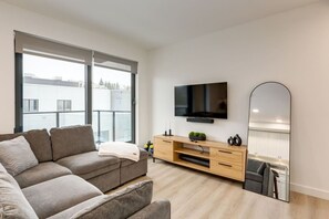 Ein modernes Wohnzimmer mit einer Couch, einem Fernseher, einem Holz-TV-Schrank und einem großen Spiegel.