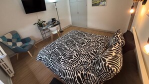 Een slaapkamer met een bed, een bureau, een stoel, een televisie en een kledingkast.