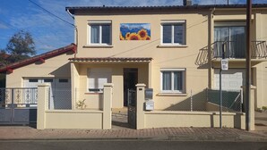 Een gebouw met twee verdiepingen, een beige gevel en een balkon op de tweede verdieping, met een bord waarop een 50m halte aangegeven staat.