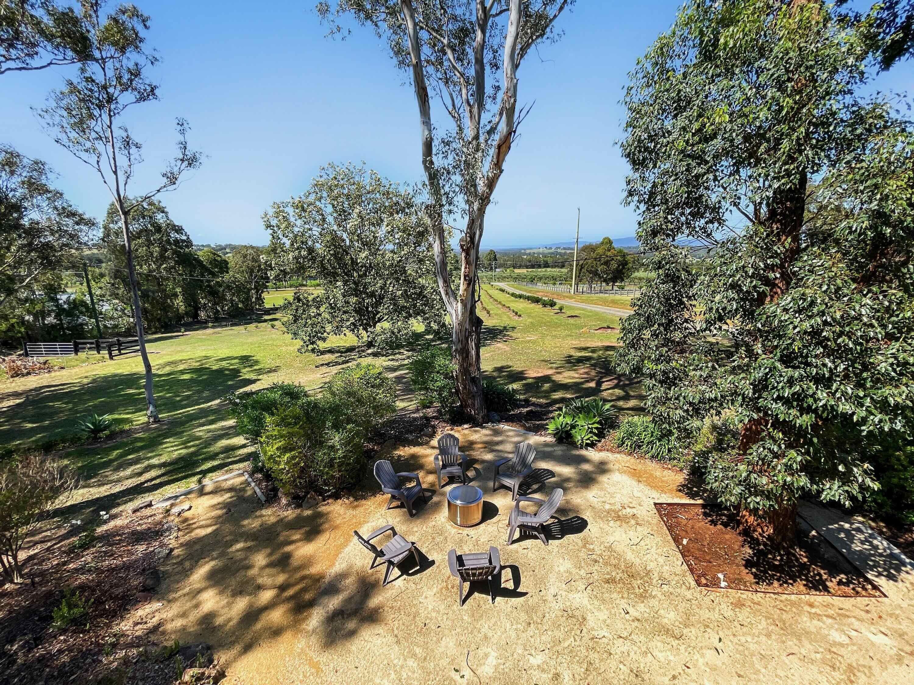 A patio area with outdoor furniture, surrounded by trees and a view of a rural landscape.