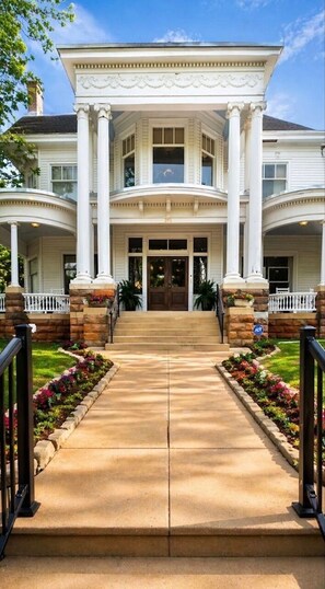A two-story building with a central entrance flanked by columns, a covered porch, and a symmetrical facade. - The Judge's Chambers (Guthrie)