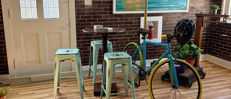 A room with a wooden floor, a bicycle, a painting, and a door with frosted glass panels.