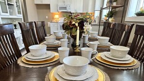 A dining table set with white plates, bowls, and cups, surrounded by dark wooden chairs. - The Judge's Chambers (Guthrie)