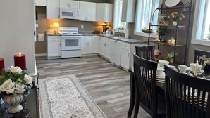 A modern kitchen with white cabinets, a built-in oven, and a dining area with a table set for four. - The Judge's Chambers (Guthrie)