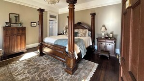 A four-poster bed with a chandelier, a wooden wardrobe, and a nightstand with a lamp. - The Judge's Chambers (Guthrie)