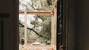 An open door leading to a wooden deck with a bench and cushions. - Stay & Play at the Charming Woodlawn Cottage (Hot Springs)