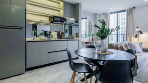 A modern kitchen with a dining area, featuring a round table and chairs, a refrigerator, and a microwave.