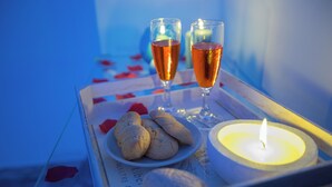 A tray with two glasses of amber liquid, a lit candle, and a plate of cookies on a table with a blue background.