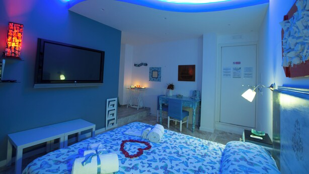 A bedroom with a bed, a desk, a chair, and a TV.